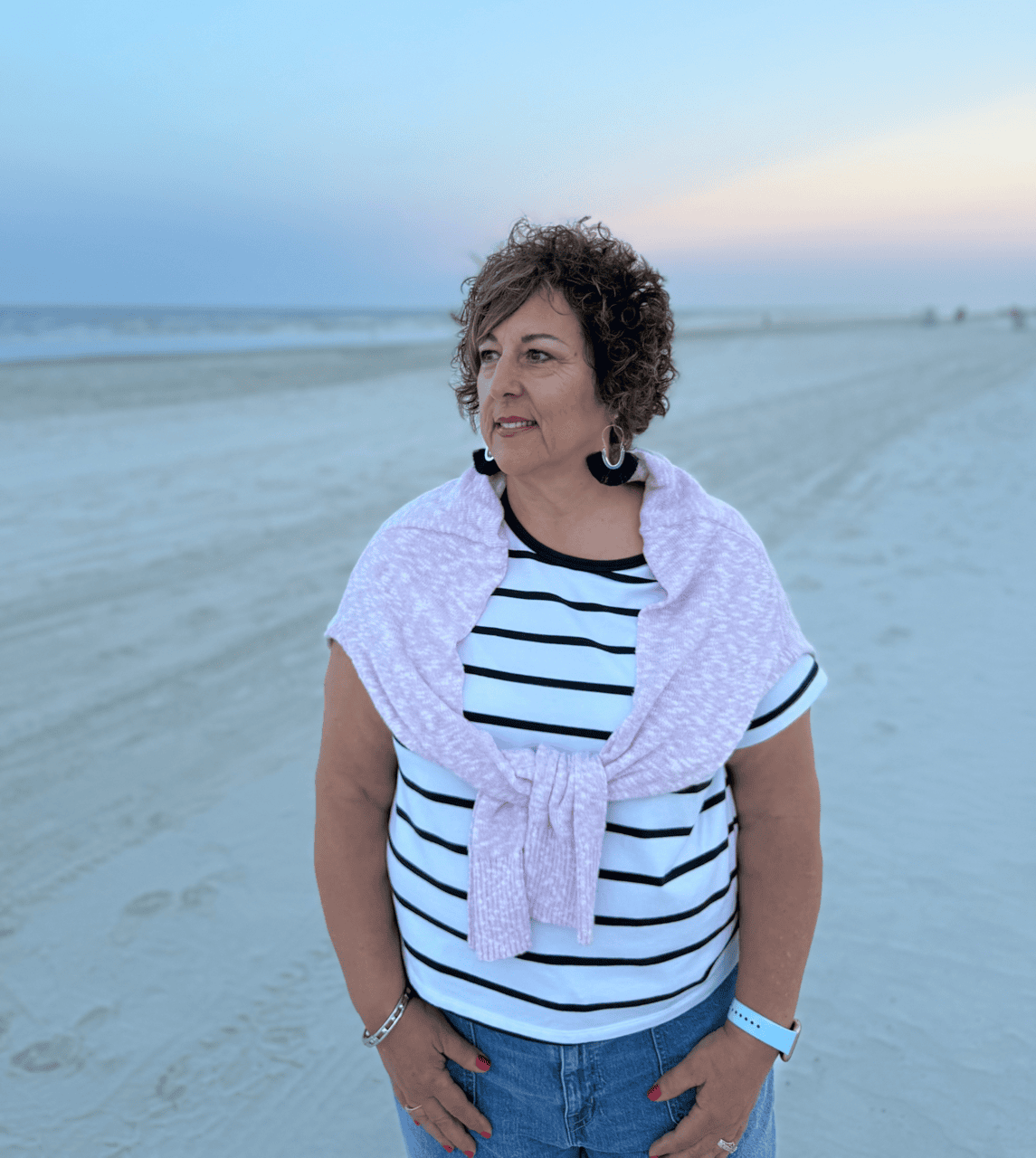 Grieving mom on the beach looking off to the distance and thinking of the child she lost